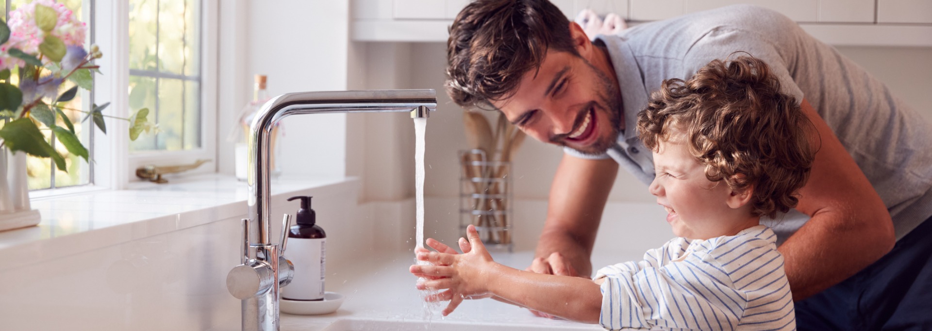 father helping son wash hands